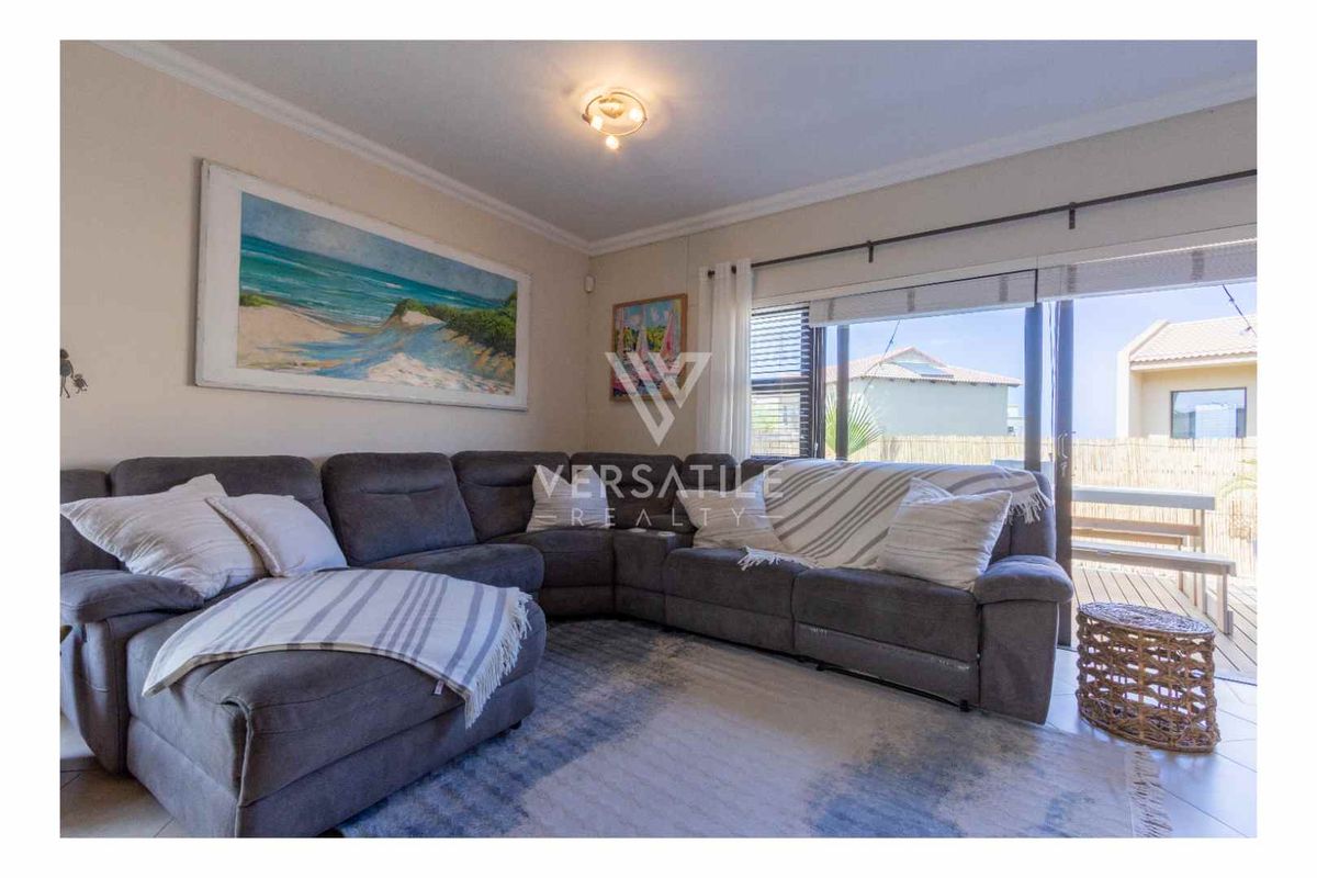 A comfortable living room featuring tiled flooring, crown molding, and large sliding glass doors that provide direct access to an outdoor patio area.