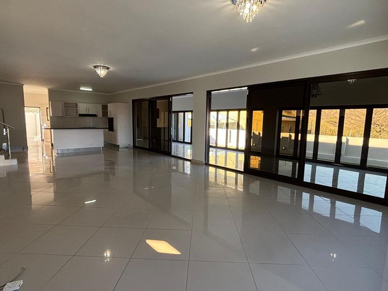 Spacious open-plan living area featuring large sliding glass doors, polished tile flooring, and an integrated kitchen with modern cabinetry.