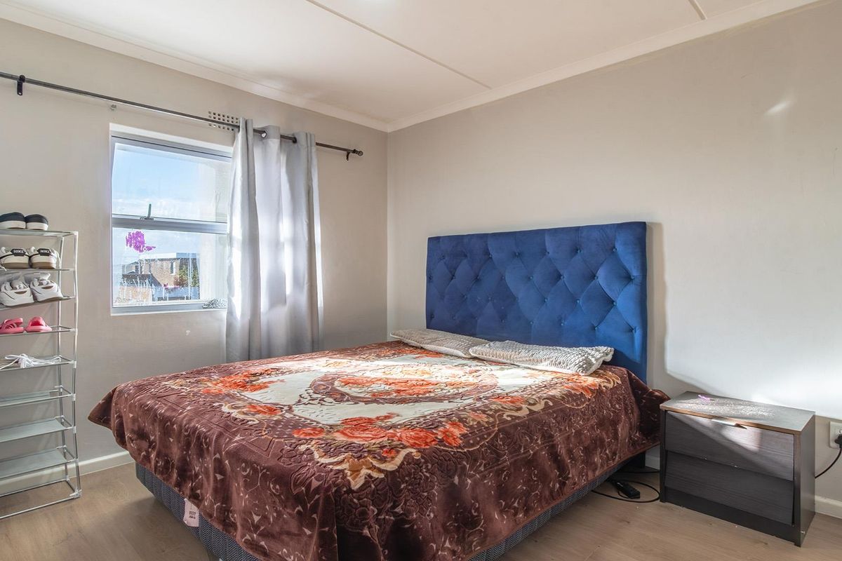 A bedroom featuring laminate flooring and a window with natural light, providing a functional space for rest.