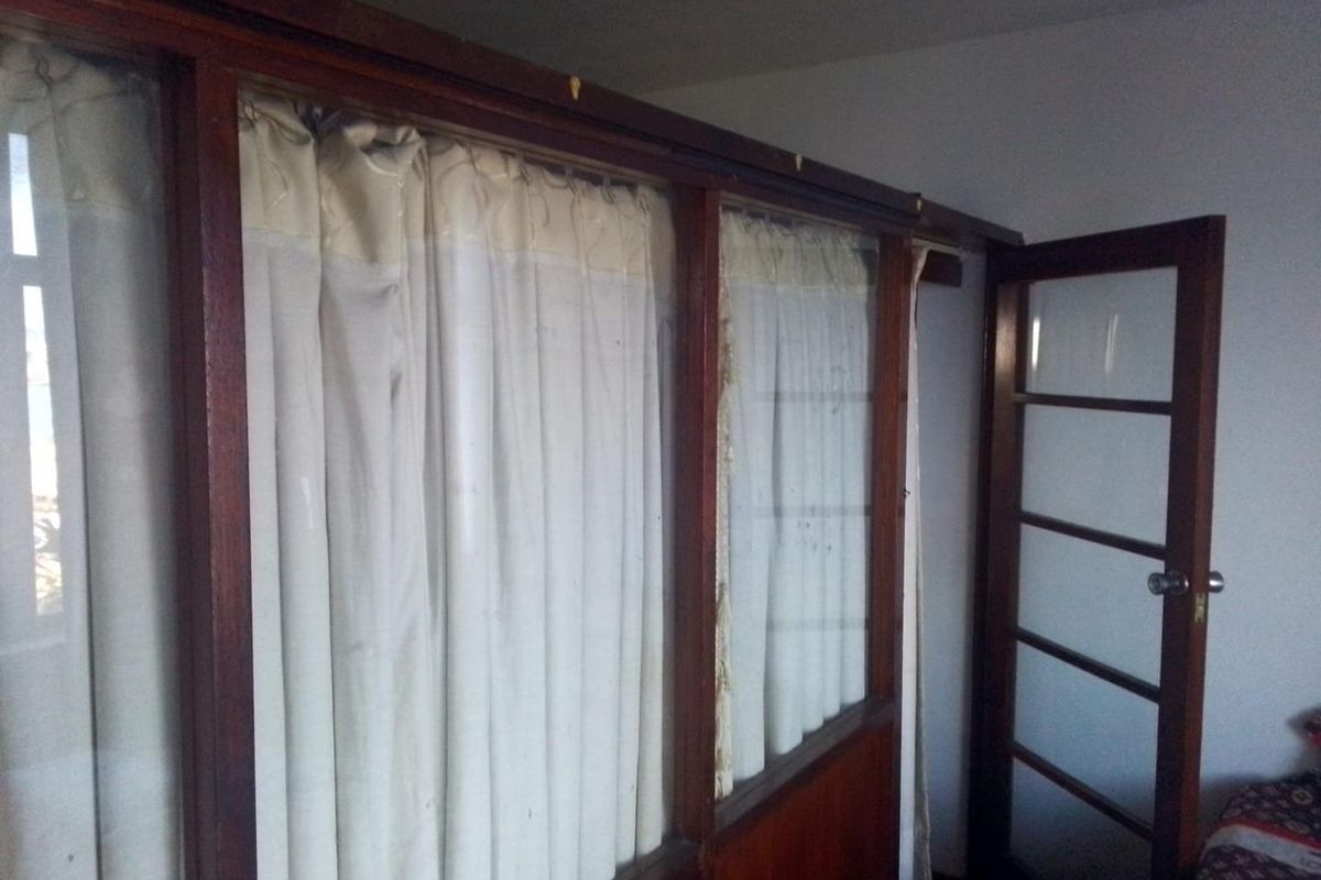 Bedroom interior featuring a dated timber-framed glass partition and matching glass door, showing signs of wear and requiring cosmetic updates.
