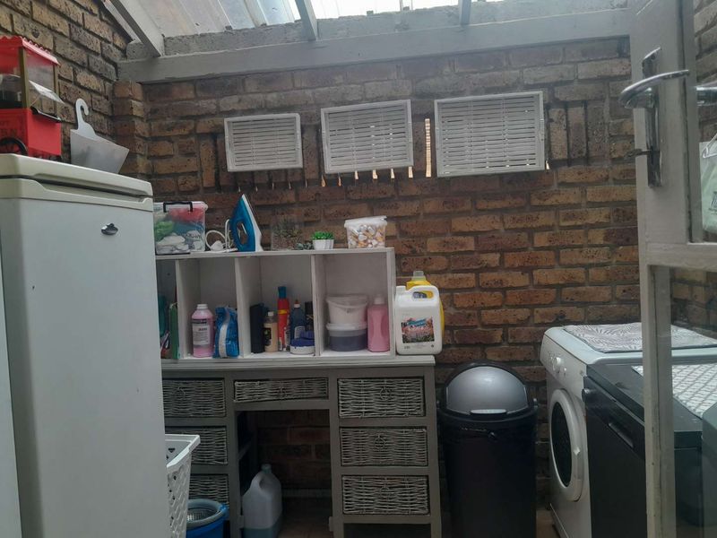 A functional laundry area featuring exposed brick walls and a translucent roof, providing a practical utility space for washing and storage.