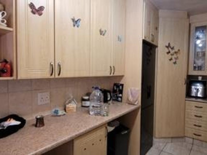 A functional kitchen featuring light-toned laminate cabinetry, tiled backsplash, and ample counter space with integrated storage solutions.