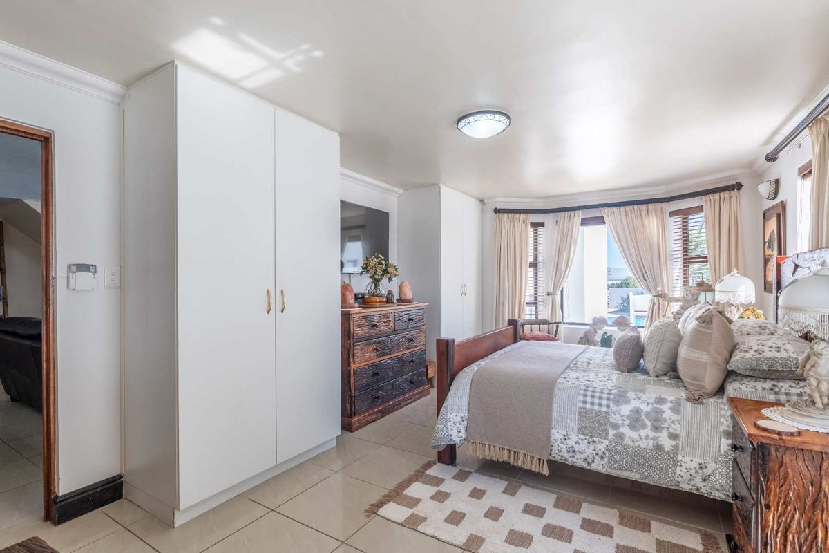 Spacious bedroom featuring tiled flooring, built-in cupboards, and a bay window that allows for natural light.