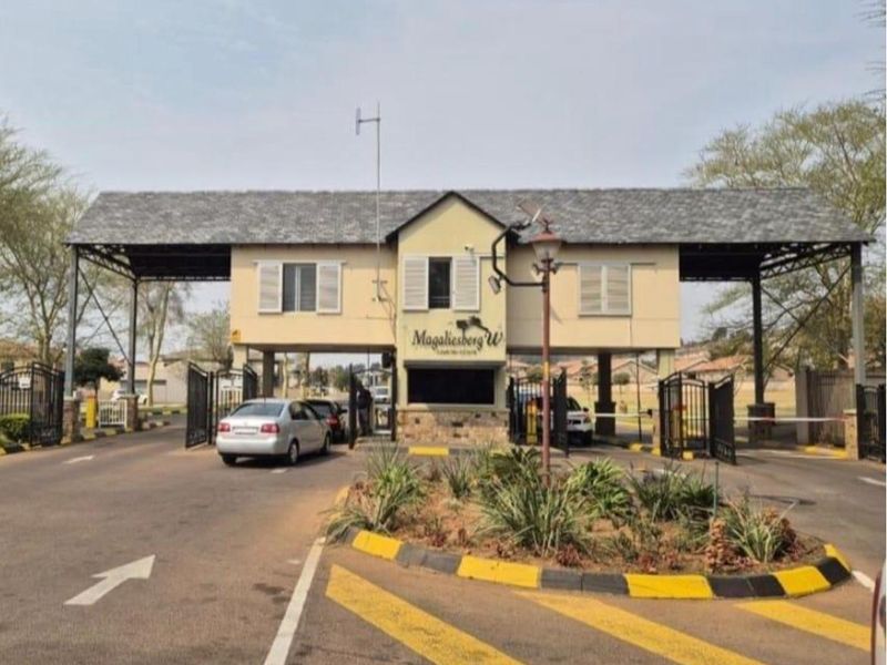 The main entrance gatehouse of the Magaliesberg residential estate, featuring a secure access point with boom gates and landscaped traffic island.