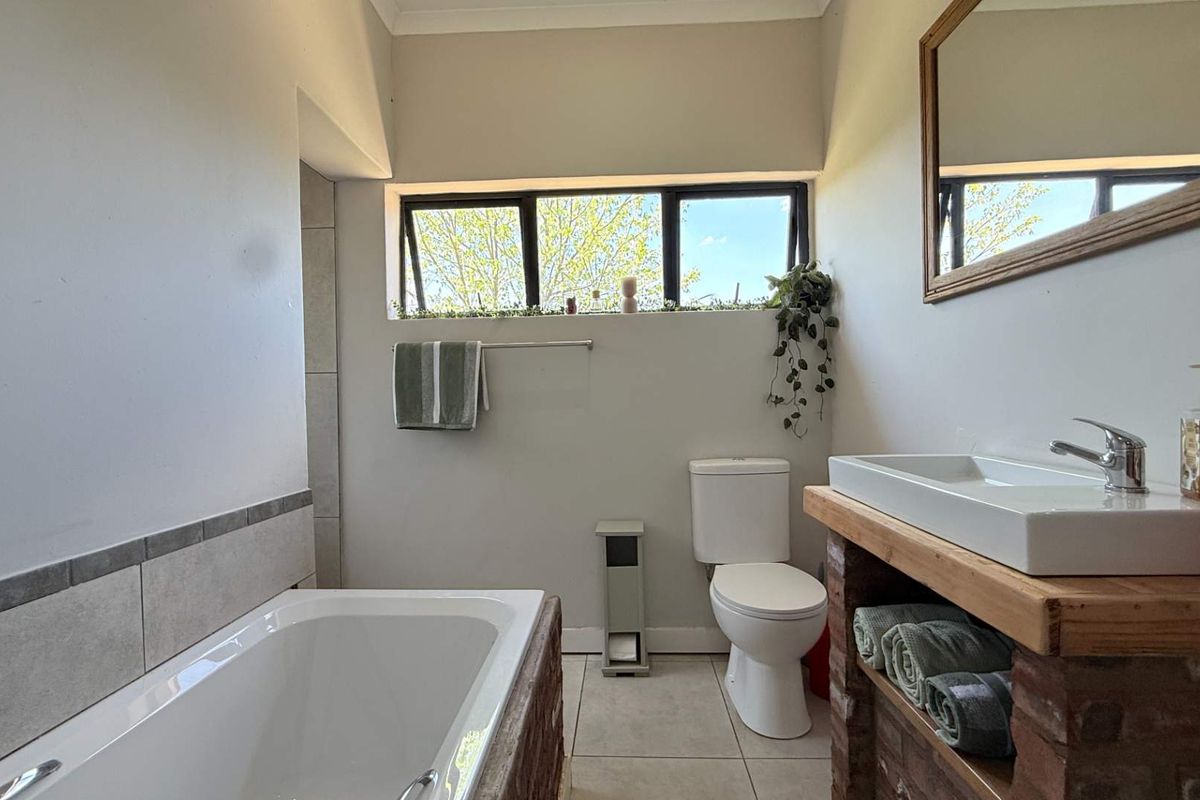 A well-maintained bathroom featuring a built-in bathtub, a modern vessel sink with a rustic vanity base, and a ceramic toilet.
