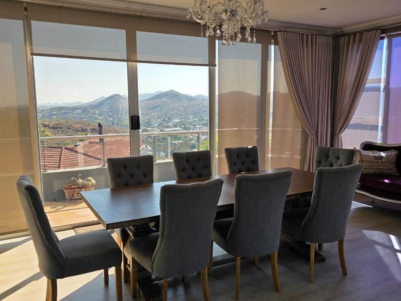 Elegant dining area featuring large windows with panoramic mountain views, modern laminate flooring, and recessed lighting.