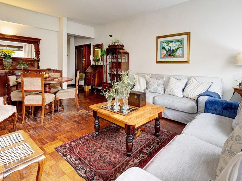 Open-plan living and dining area featuring classic parquet flooring and neutral wall finishes, offering a warm and traditional atmosphere.