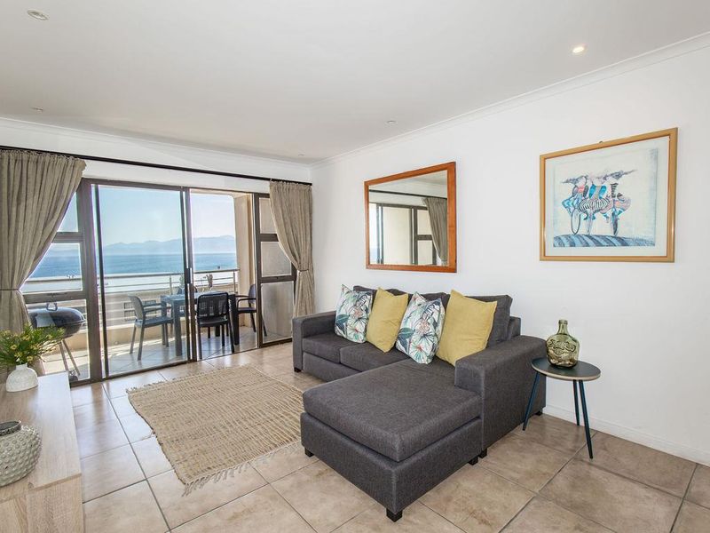 Bright living room featuring tiled flooring, recessed lighting, and large sliding glass doors opening onto a balcony with scenic ocean views.