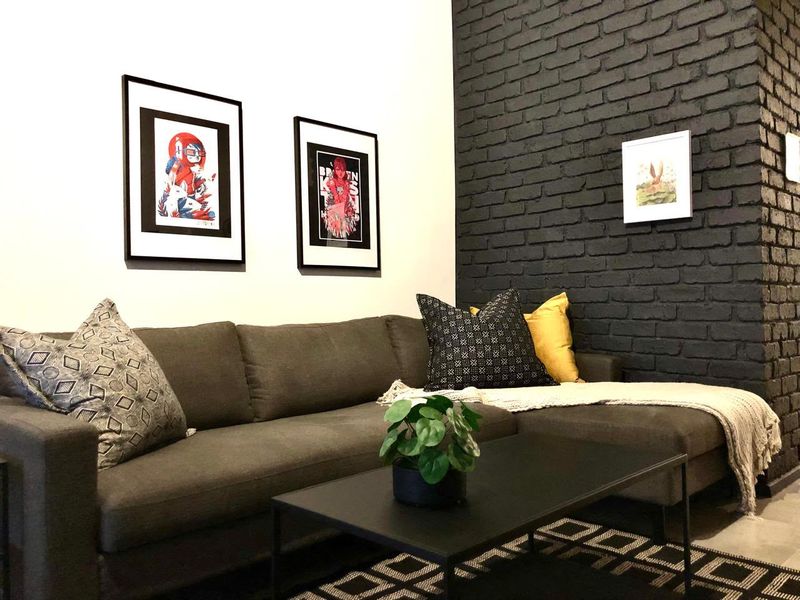 A modern living room featuring a striking dark painted exposed brick feature wall, creating a contemporary and stylish atmosphere.