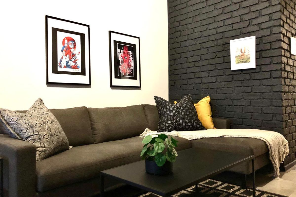 A modern living room featuring a striking dark painted exposed brick feature wall, creating a contemporary and stylish atmosphere.
