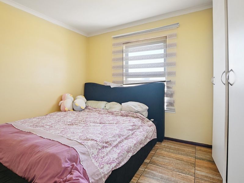 A bedroom featuring tiled flooring, a built-in wardrobe, and a window fitted with a modern roller blind.