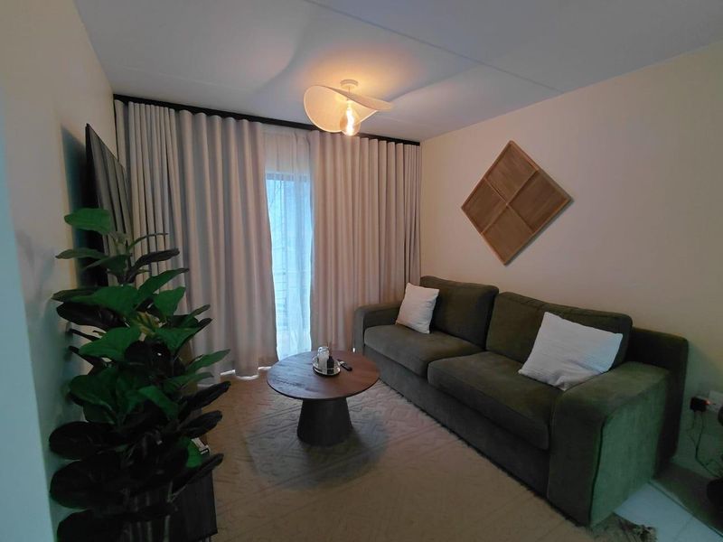 A cozy living room featuring floor-to-ceiling curtains and a central light fixture, providing a comfortable and well-lit space.