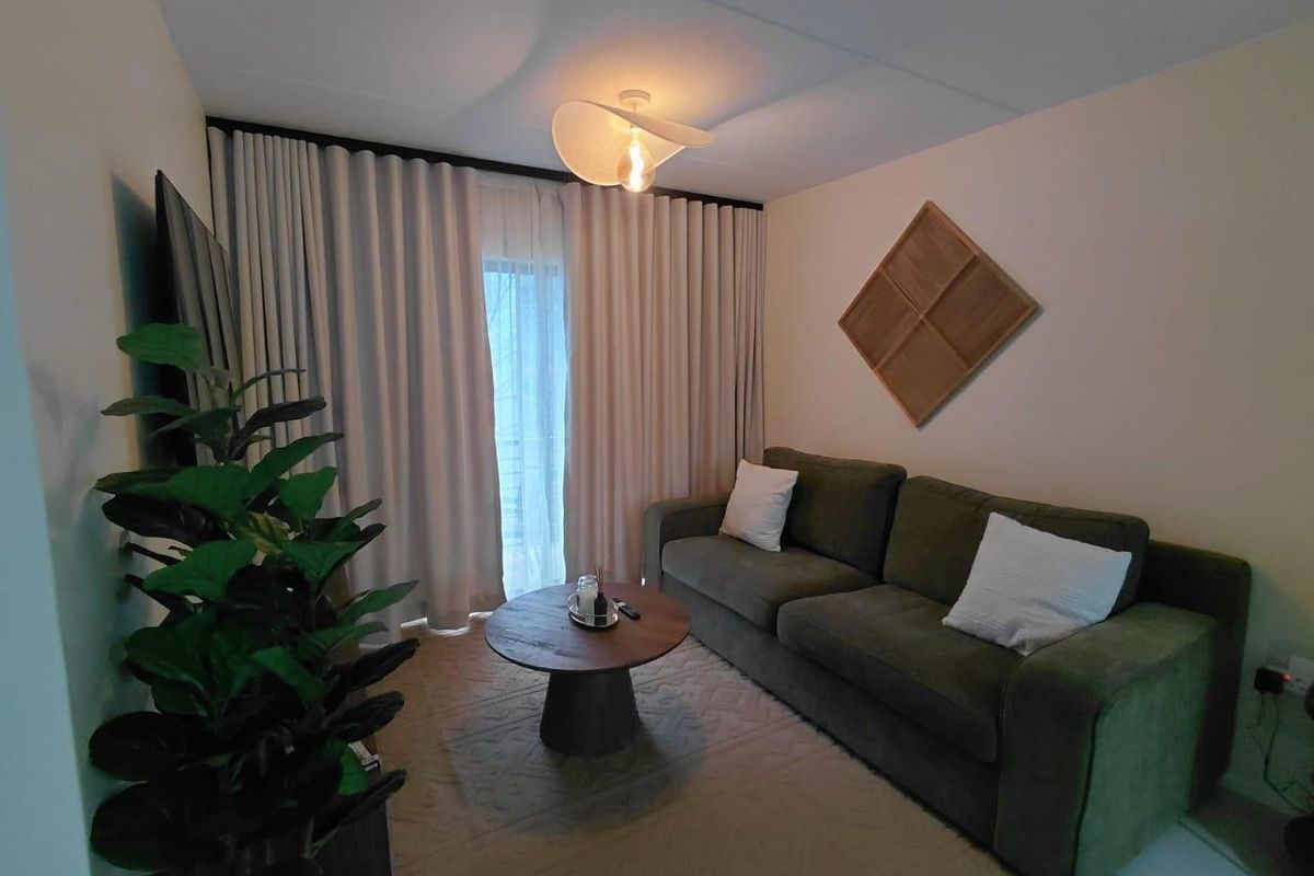 A cozy living room featuring floor-to-ceiling curtains and a central light fixture, providing a comfortable and well-lit space.