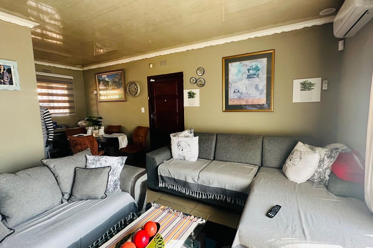 A comfortable living room featuring tiled flooring, a glossy ceiling finish, and a wall-mounted air conditioning unit.
