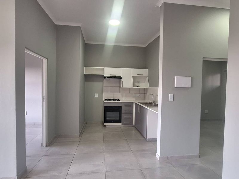 A clean, modern kitchen featuring built-in cabinetry, a gas hob, electric oven, and tiled flooring in an open-plan layout.