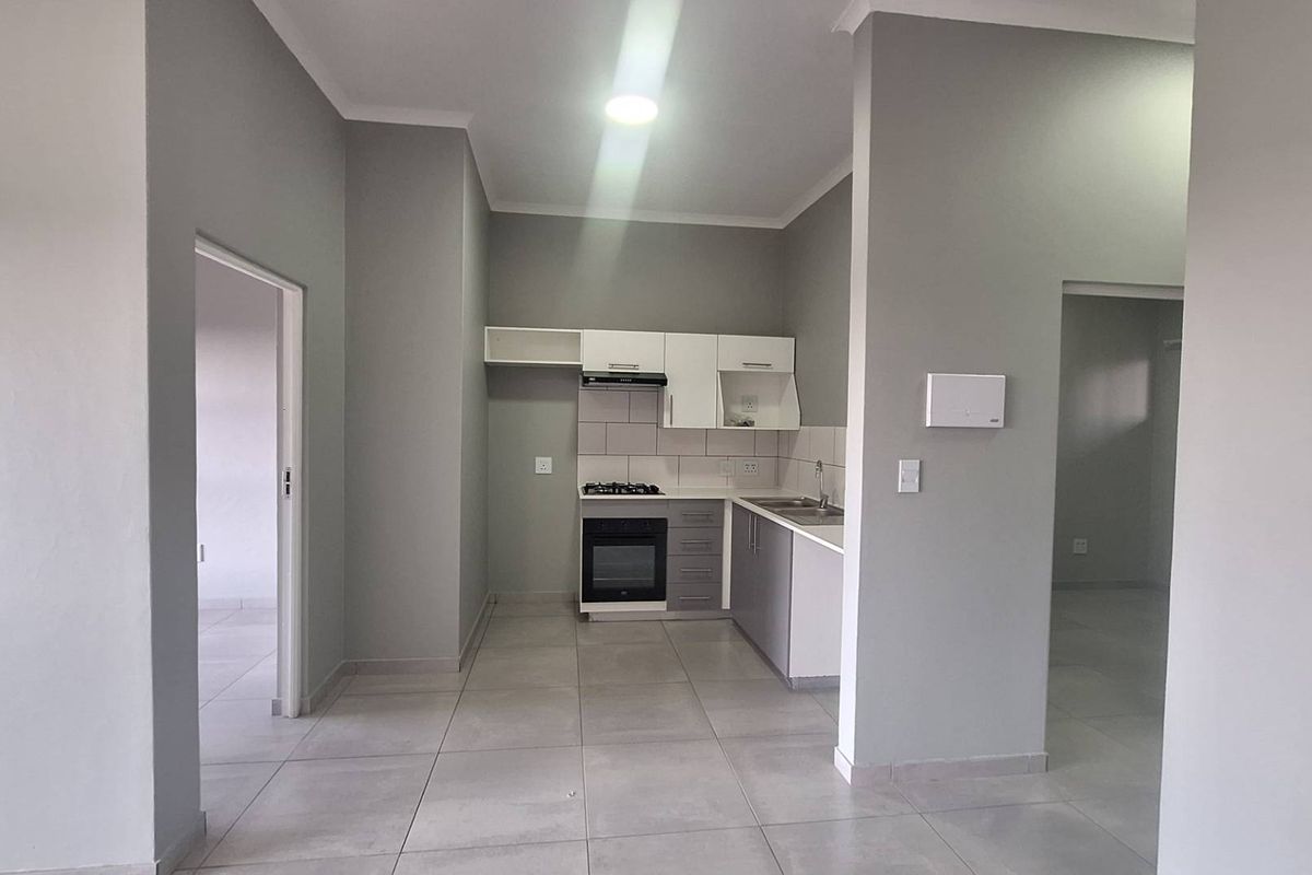 A clean, modern kitchen featuring built-in cabinetry, a gas hob, electric oven, and tiled flooring in an open-plan layout.