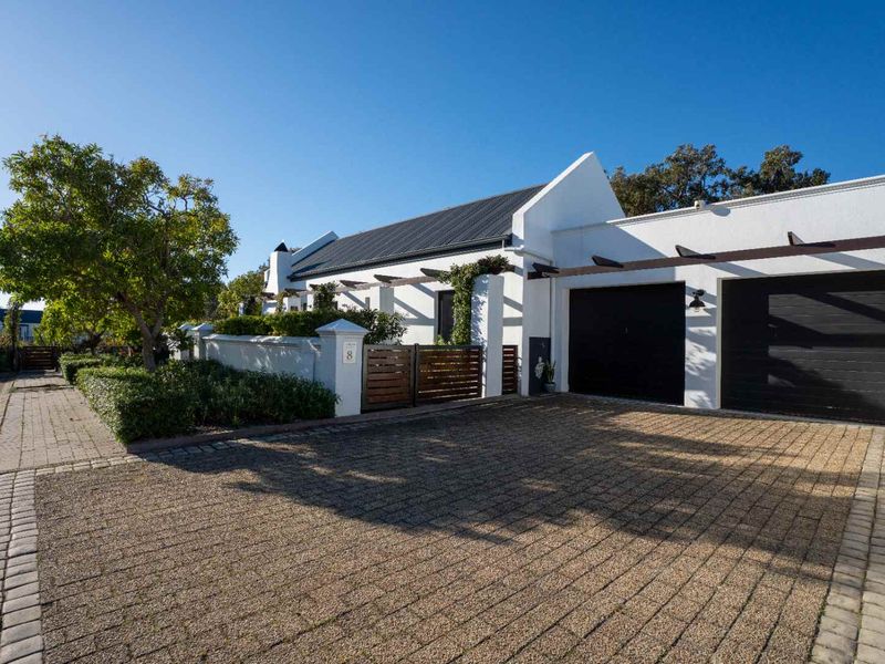 Front elevation of a well-maintained house featuring a paved driveway, double garage, and timber pergola accents.