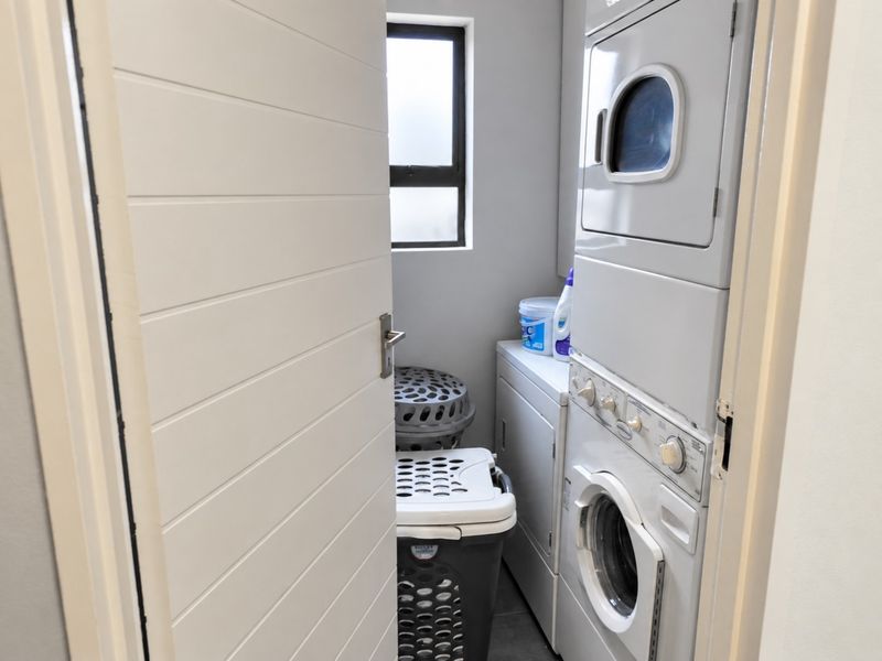 A compact laundry room featuring a stacked washer and dryer unit and a window for natural light.