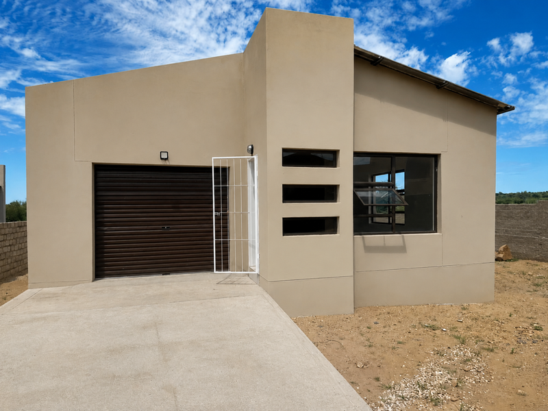 Modern single-story house exterior featuring a roller garage door, security gate, and horizontal slit windows with a concrete driveway.