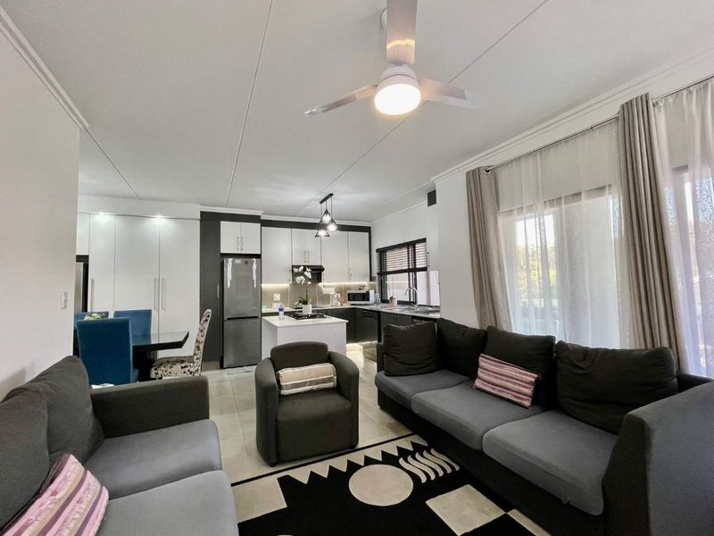 Modern open-plan living area featuring a contemporary kitchen with built-in cabinetry, a central island, and seamless flow to the lounge and dining space.