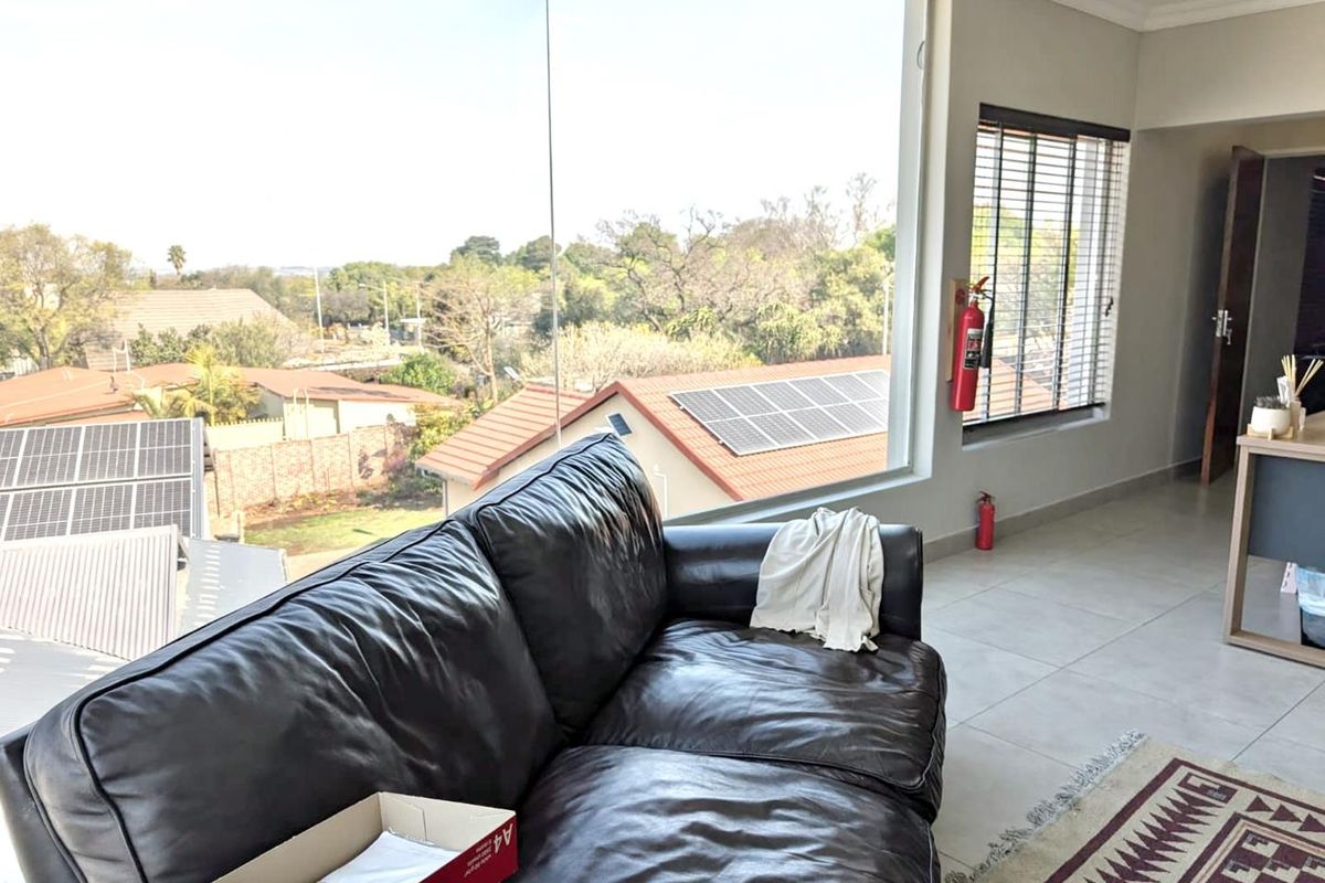 Bright office space featuring large floor-to-ceiling windows with expansive neighbourhood views, tiled flooring, and integrated safety equipment.