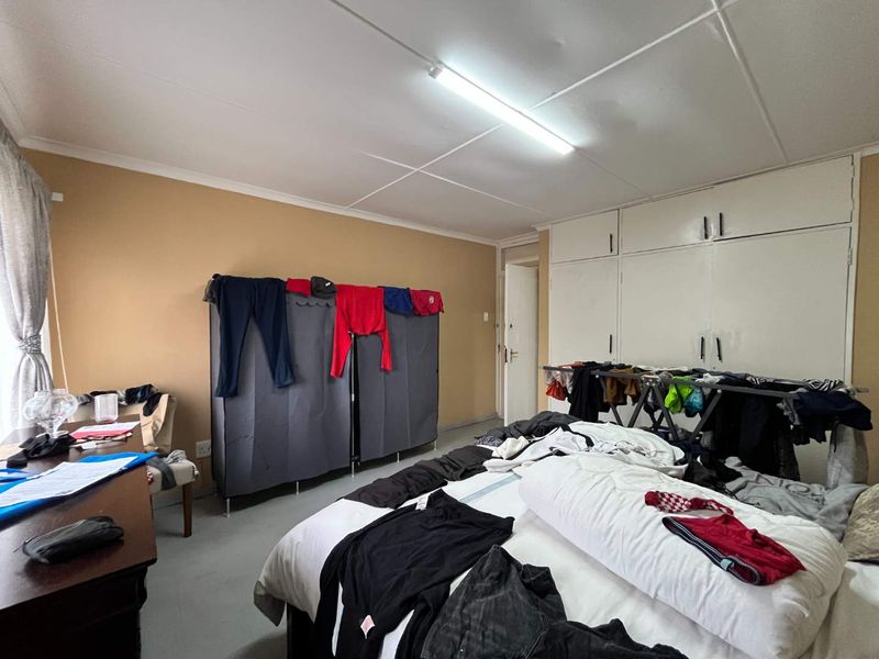 A bedroom featuring built-in cupboards and a tiled ceiling, currently in need of maintenance and cosmetic updates.