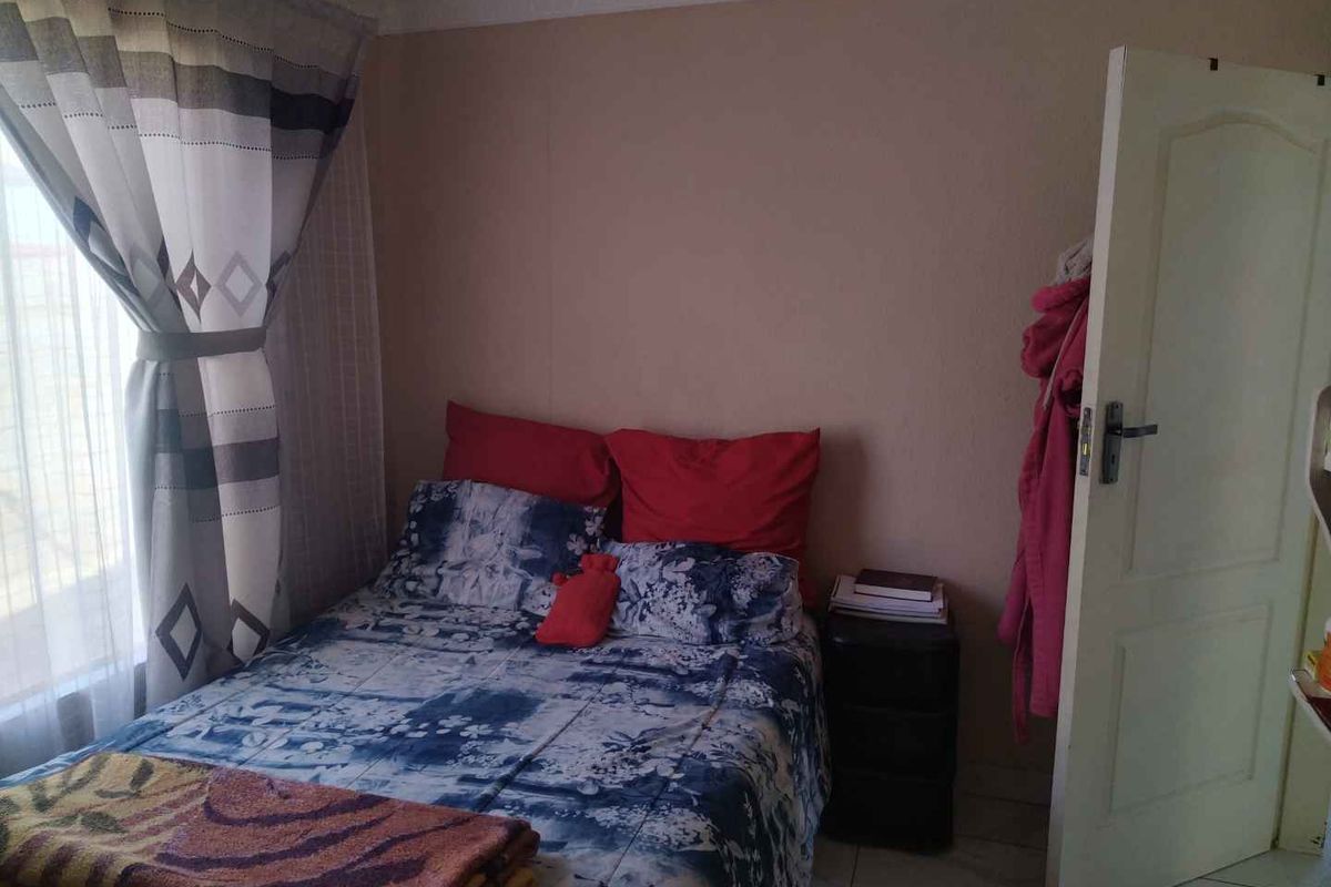 A standard bedroom featuring tiled flooring, crown molding, and a window with curtain tracks.