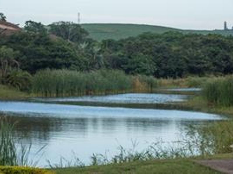 A scenic view of a natural lake surrounded by lush greenery and rolling hills.