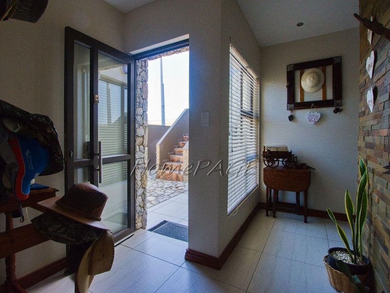 Welcoming entrance hall featuring tiled flooring, a decorative stone feature wall, and natural light through a large window with venetian blinds.