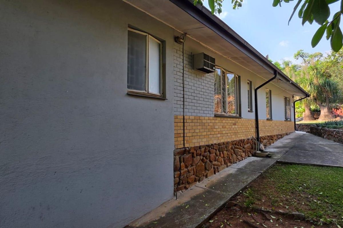 A view of the rear exterior facade featuring a mix of stone, brick, and plastered finishes with a concrete walkway along the building perimeter.