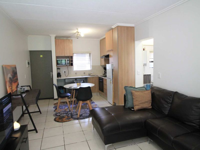 Open-plan living area featuring a functional kitchen with built-in cabinetry, oven, and extractor fan, seamlessly connected to the lounge space.