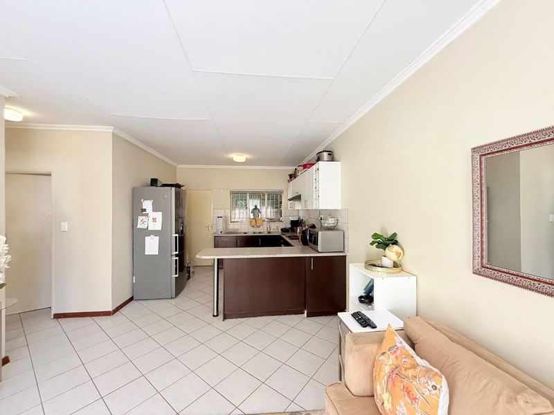 Open plan kitchen and living area featuring tiled flooring, breakfast bar, and functional cabinetry, providing a practical layout for daily living.