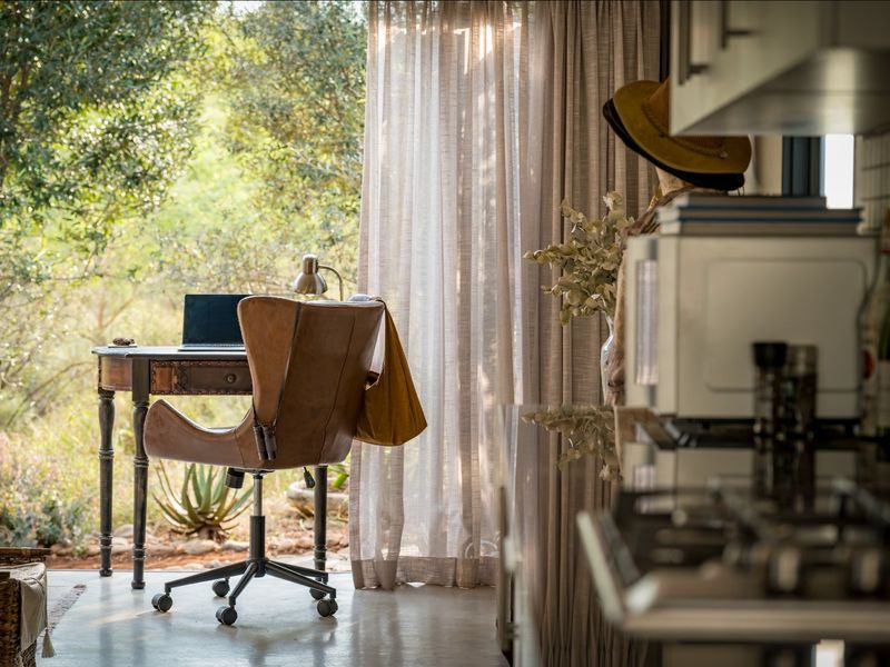 An open-plan living space featuring polished concrete floors and large glass doors that provide seamless access to the natural garden surroundings.