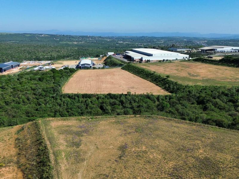 Aerial view of an industrial park featuring multiple warehouse structures surrounded by expansive undeveloped land and natural vegetation.