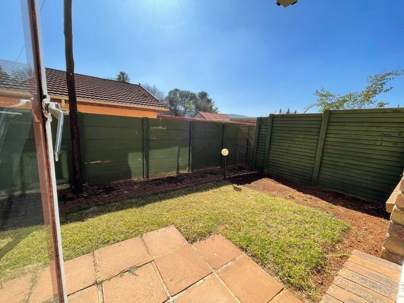 A private rear garden featuring a paved patio area, a small lawn, and perimeter boundary fencing.