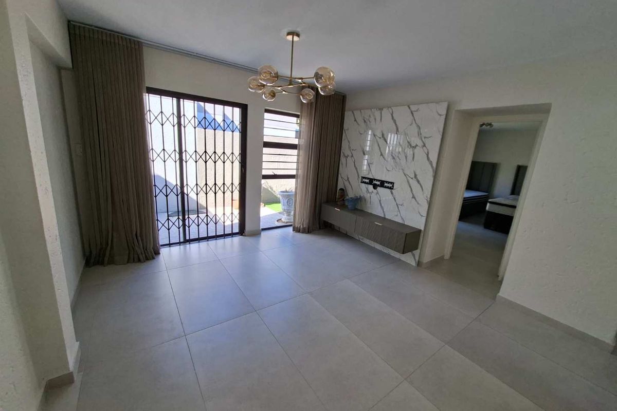 Spacious living area featuring large format floor tiles, a marble-look feature wall with a floating console, and direct access to the outdoor area.