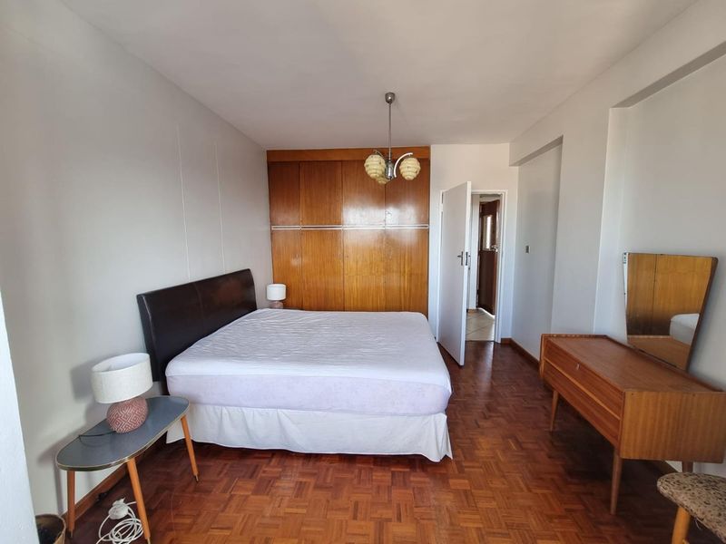 A bedroom featuring classic parquet flooring and extensive built-in wooden cabinetry, offering ample storage space and a traditional aesthetic.