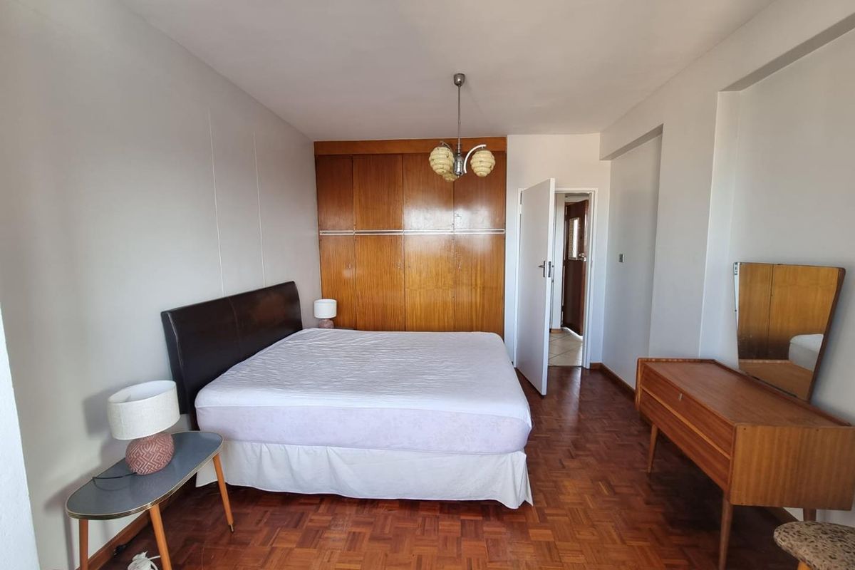 A bedroom featuring classic parquet flooring and extensive built-in wooden cabinetry, offering ample storage space and a traditional aesthetic.