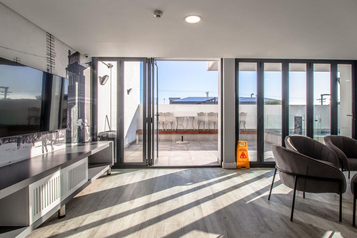 Modern living area featuring light wood-look flooring and large bi-fold doors opening onto a private balcony, creating a seamless indoor-outdoor flow.