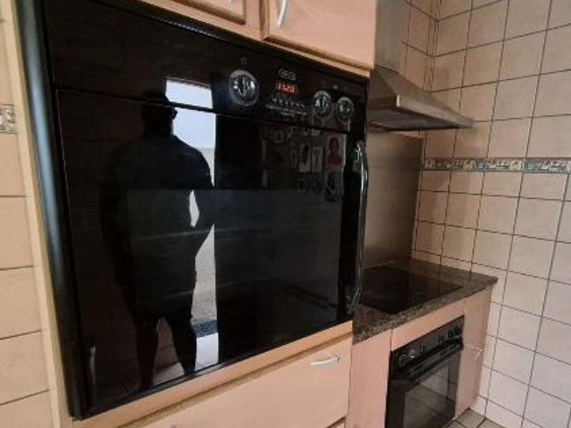 Kitchen area featuring built-in oven, hob, extractor fan, and tiled splashback with laminate cabinetry.