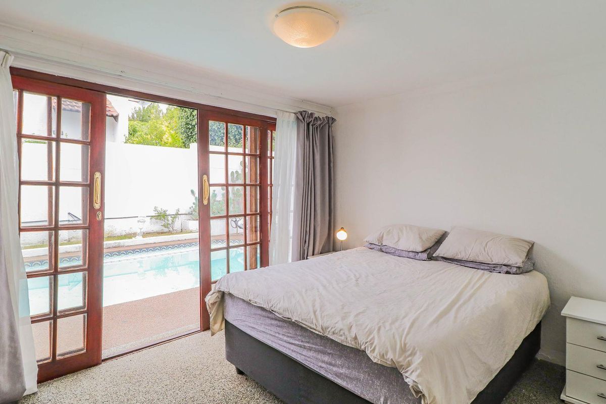 Bedroom featuring sliding wooden doors that open directly onto a private swimming pool area, providing natural light and outdoor access.