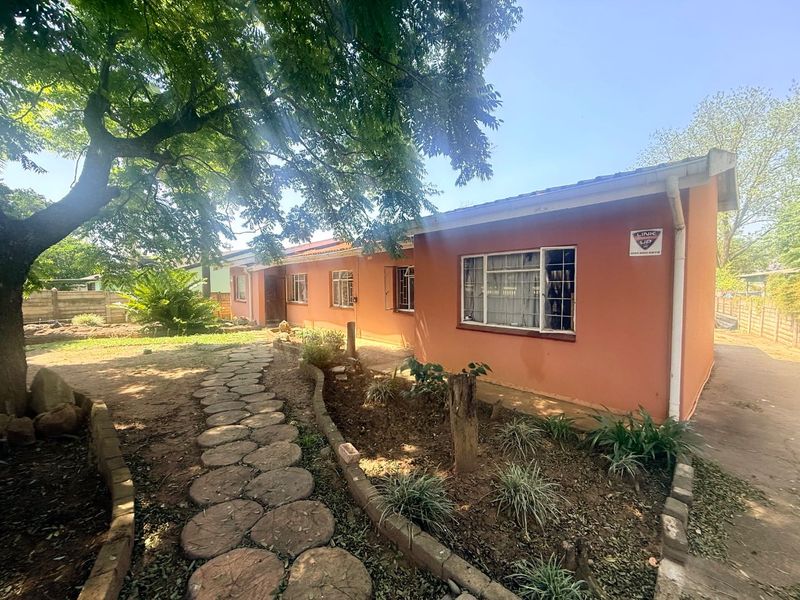 Rear exterior view of the house featuring a stone pathway, established garden, and security system.