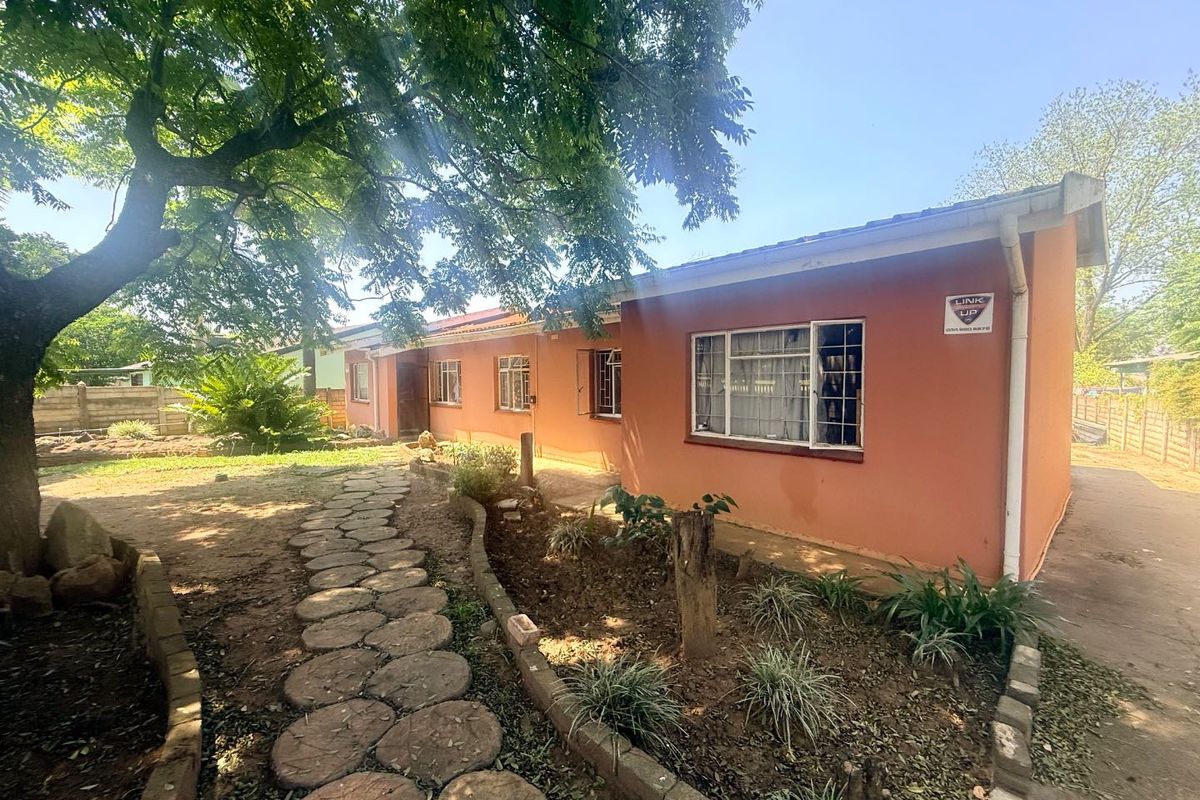 Rear exterior view of the house featuring a stone pathway, established garden, and security system.