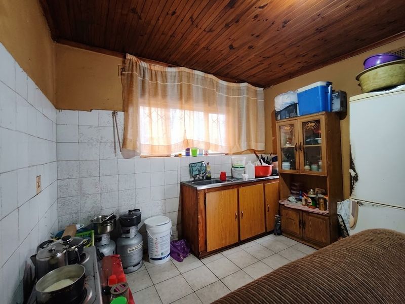 A dated kitchen featuring timber ceiling paneling, tiled splashbacks, and built-in wooden cabinetry, offering significant potential for modernization and renovation.