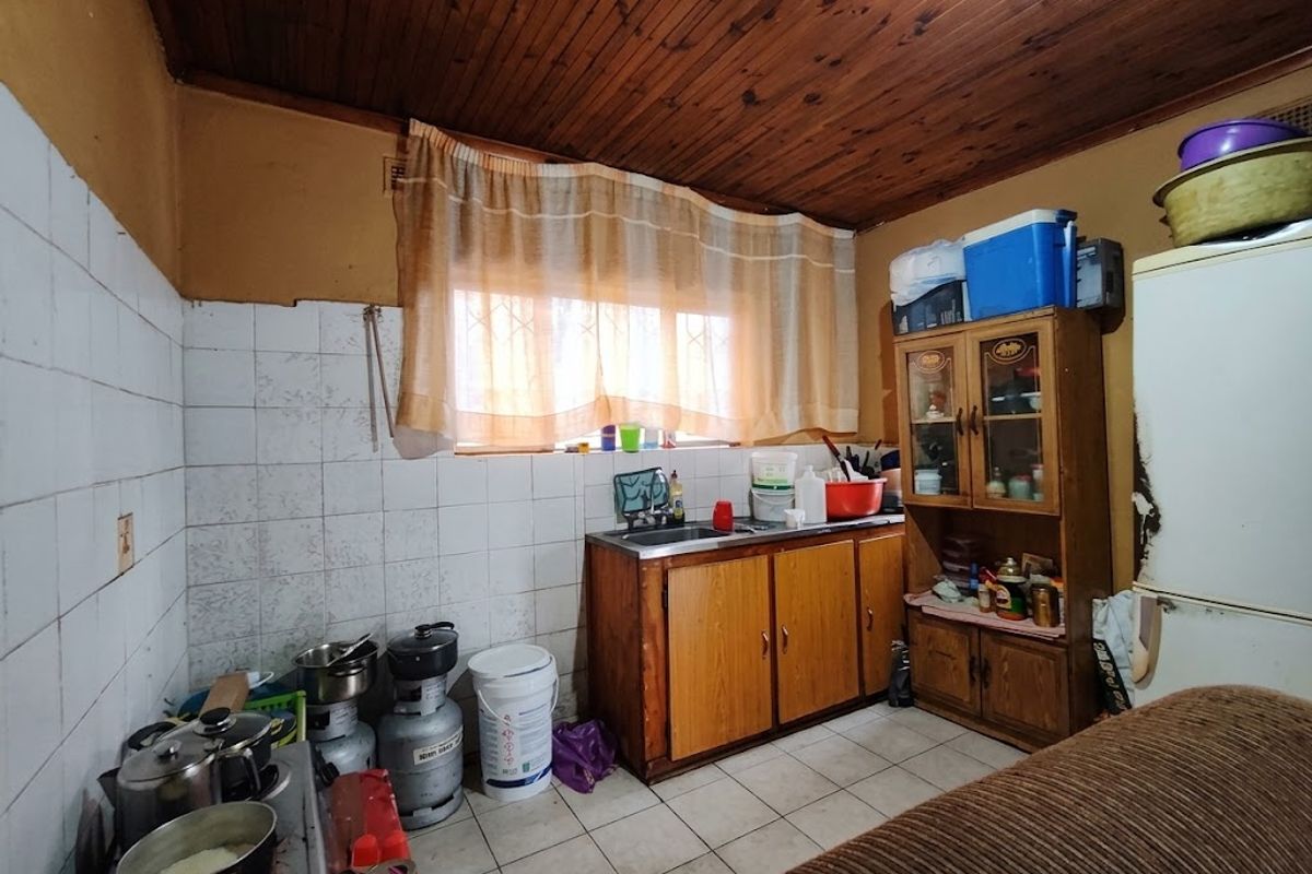 A dated kitchen featuring timber ceiling paneling, tiled splashbacks, and built-in wooden cabinetry, offering significant potential for modernization and renovation.