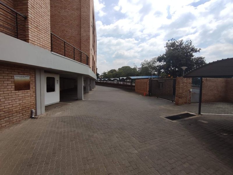 Exterior view of the apartment complex entrance featuring a paved driveway, brick facade, and secure gated access.
