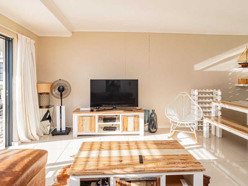 Bright open-plan living area featuring tiled flooring and a large sliding glass door providing access to the outdoor balcony space.