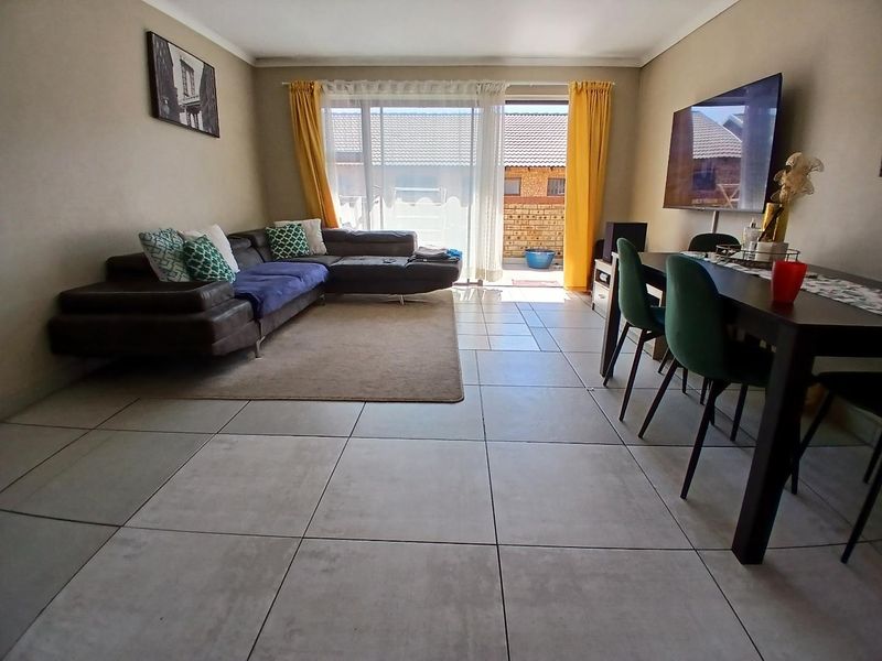 Open-plan living and dining area featuring large format floor tiles and a sliding glass door providing access to the outdoor patio.