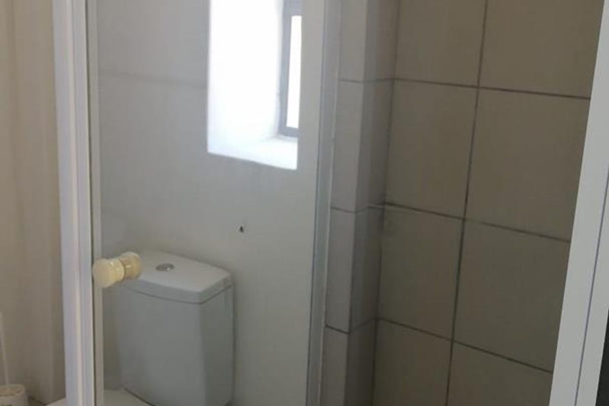 A functional bathroom featuring a tiled shower enclosure with a glass door and a standard white toilet.