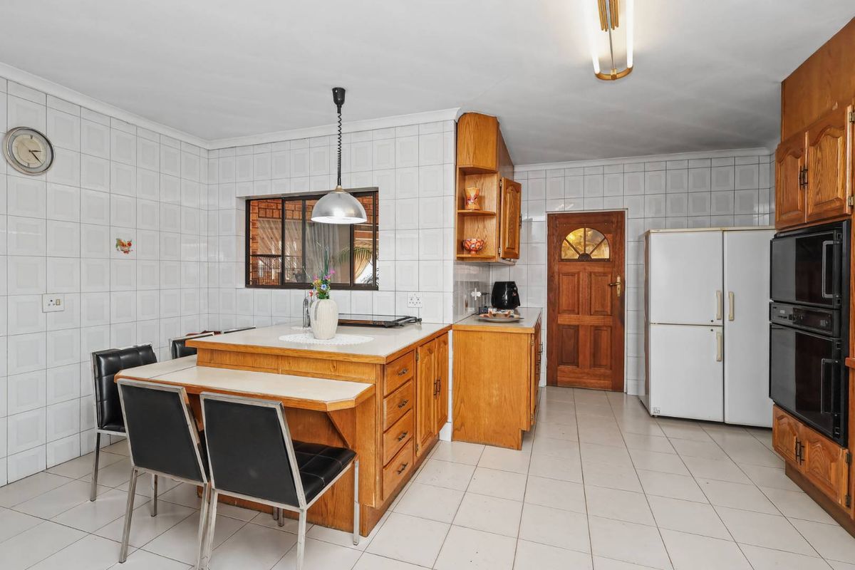 A functional kitchen featuring built-in wooden cabinetry, a central island, tiled walls, and integrated oven, offering a classic layout with potential for modern updates.